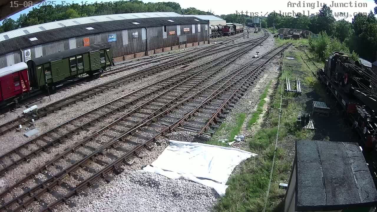 A railway yard with multiple train cars and tracks under partly cloudy skies.