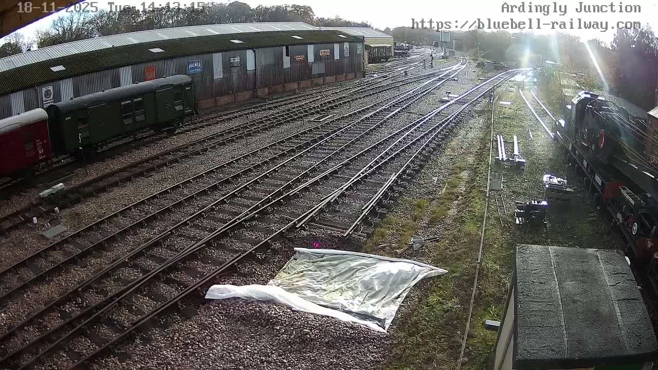 A railway yard with multiple train cars and tracks under partly cloudy skies.