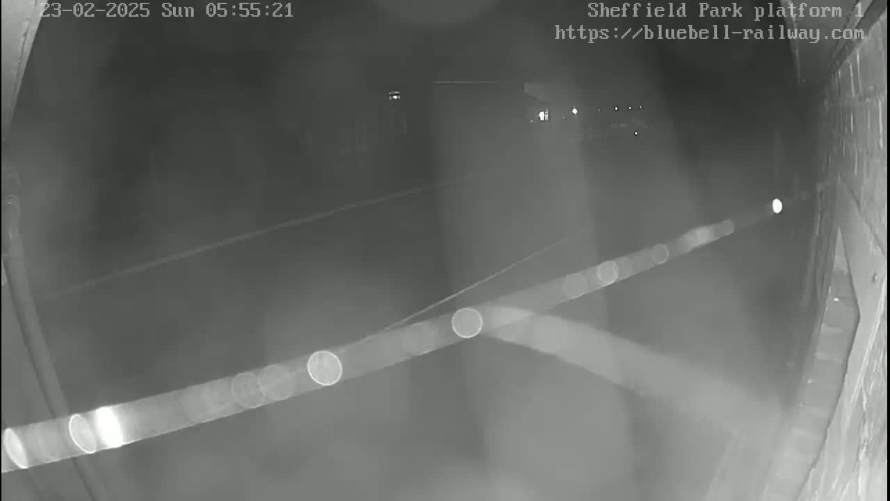 A nighttime, low-light view shows a dark platform area with faint light sources in the distance.