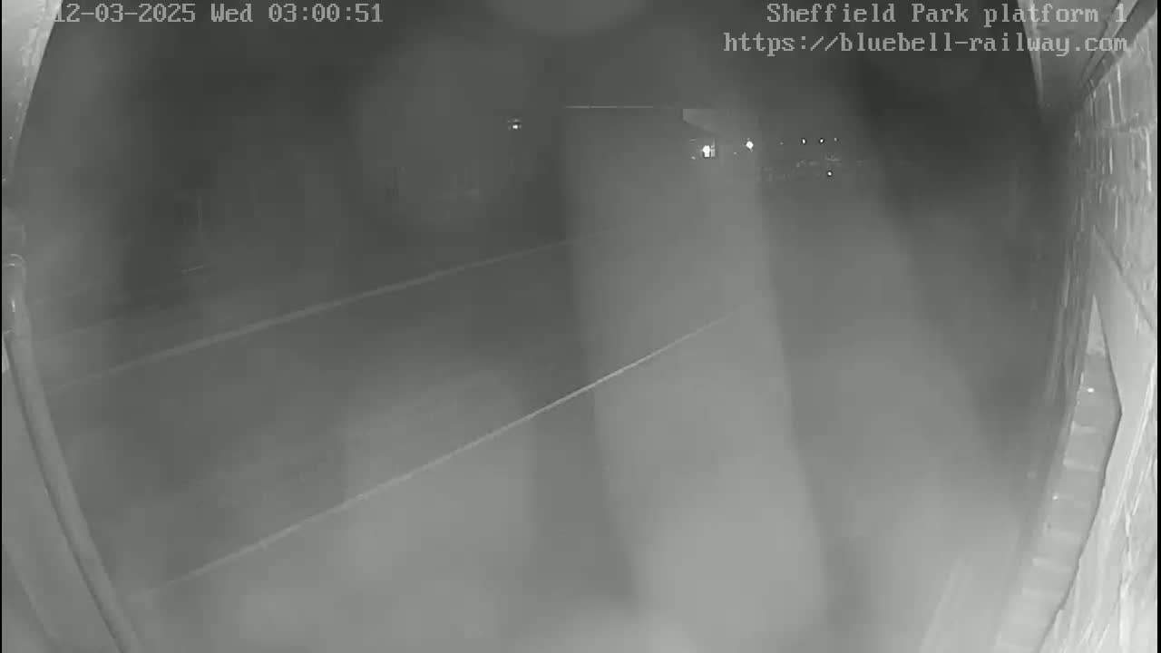 A nighttime, low-visibility view from a security camera shows a dark, empty platform with faint markings on the ground.