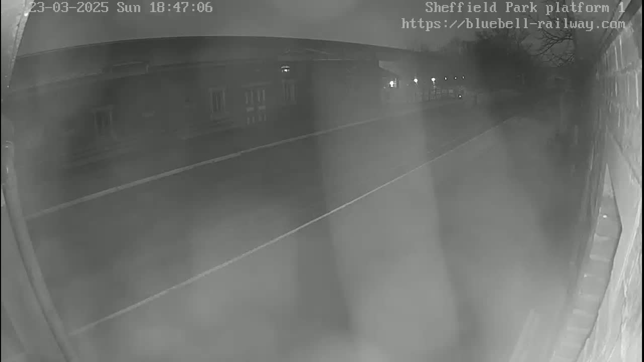 A nighttime low-light security camera view shows a mostly empty platform at a train station.