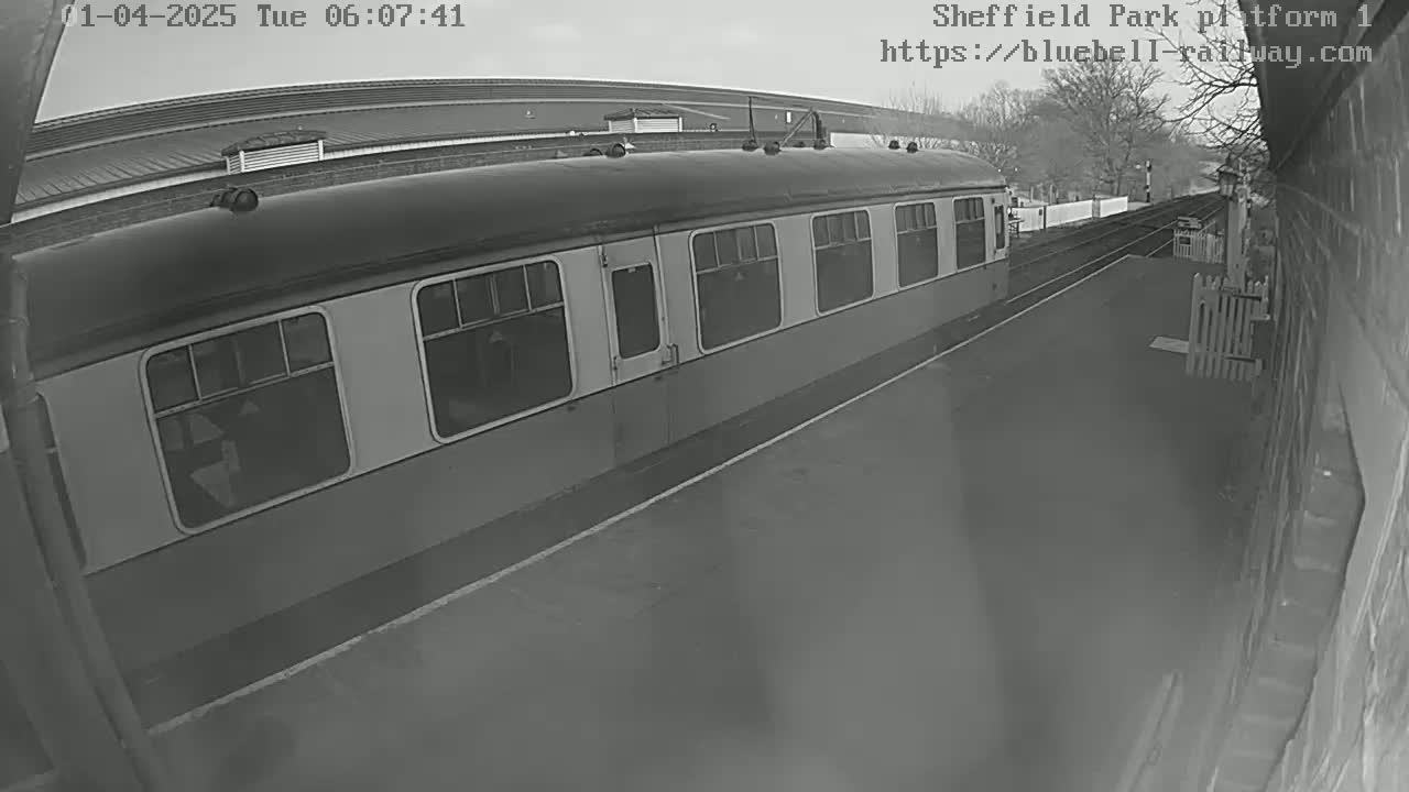 A railway carriage sits at a station platform on an overcast day.