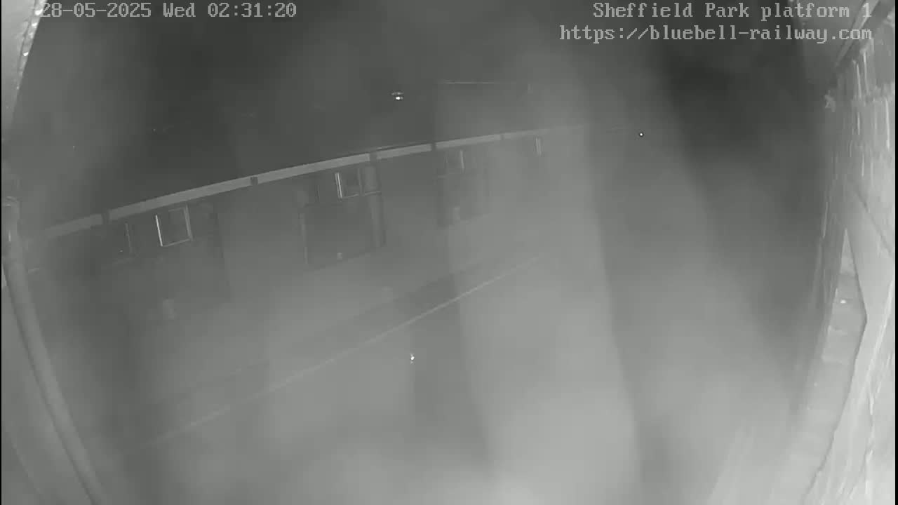 A nighttime, foggy view of a long, narrow corridor with windows along one side.