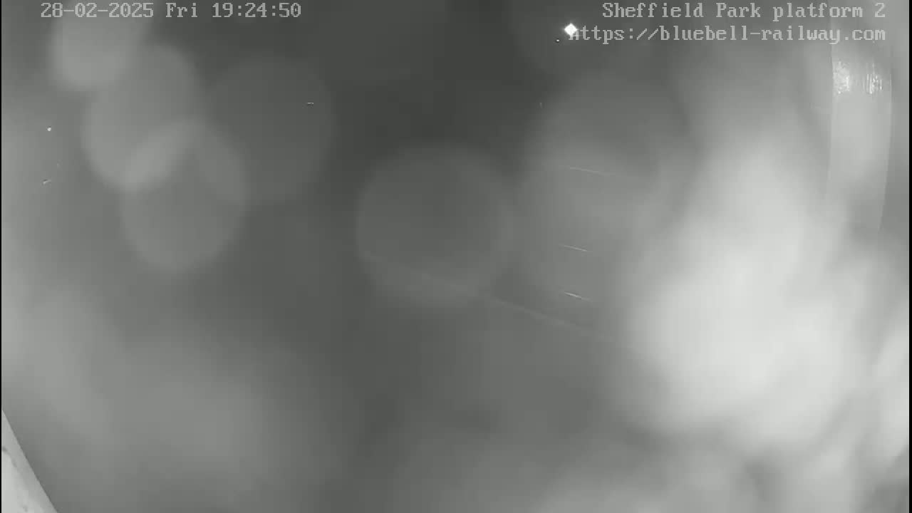 A blurry, grayscale image shows an empty, dimly lit area, possibly indoors.