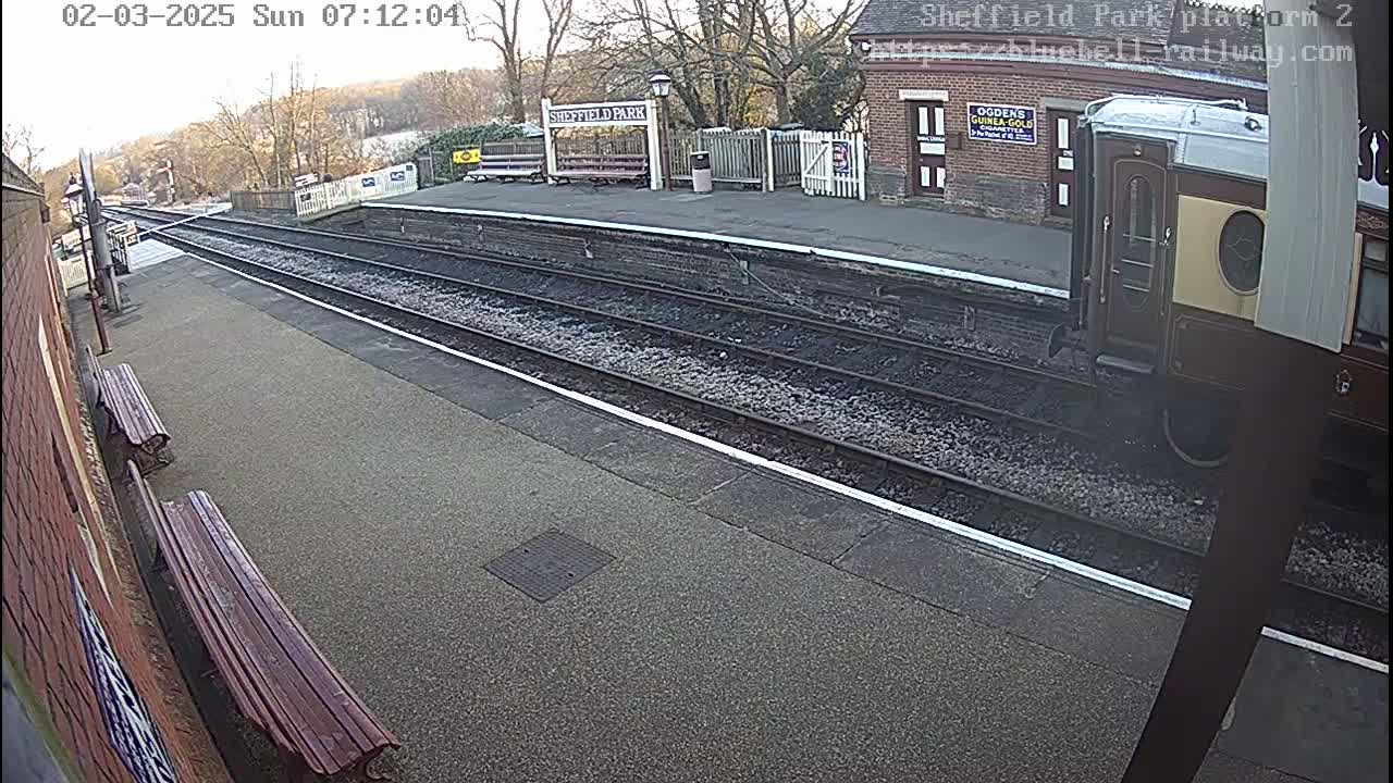 A train departs from a railway station platform on an overcast day.