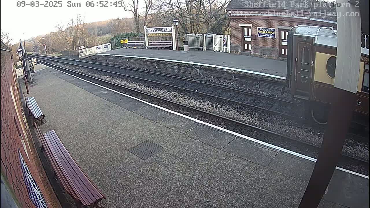 A train car is partially visible at a train station platform on an overcast day.