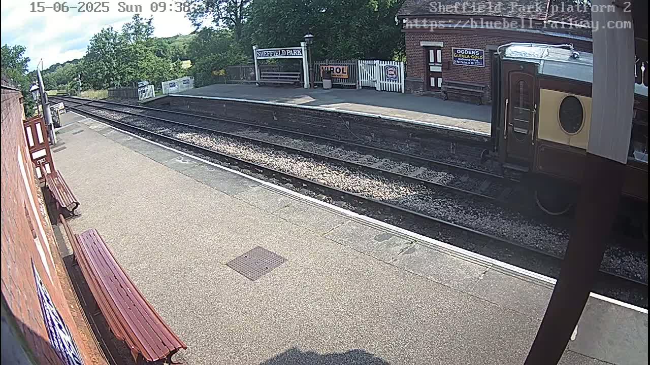A train car is partially visible at a train station platform on a sunny day.