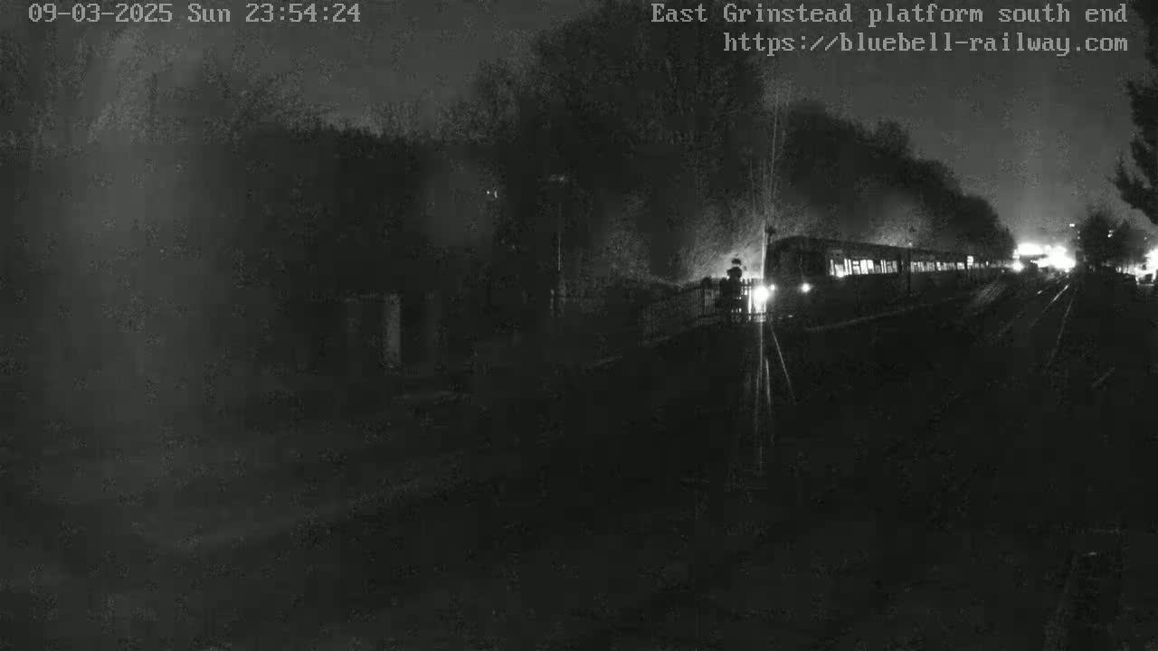 A train is departing from a dimly lit station at night.