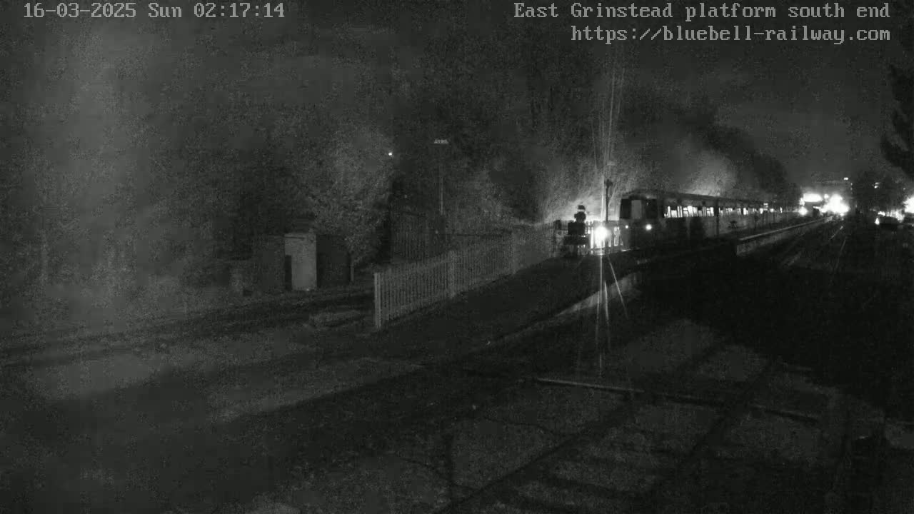 A train departs a dark, nighttime train station.