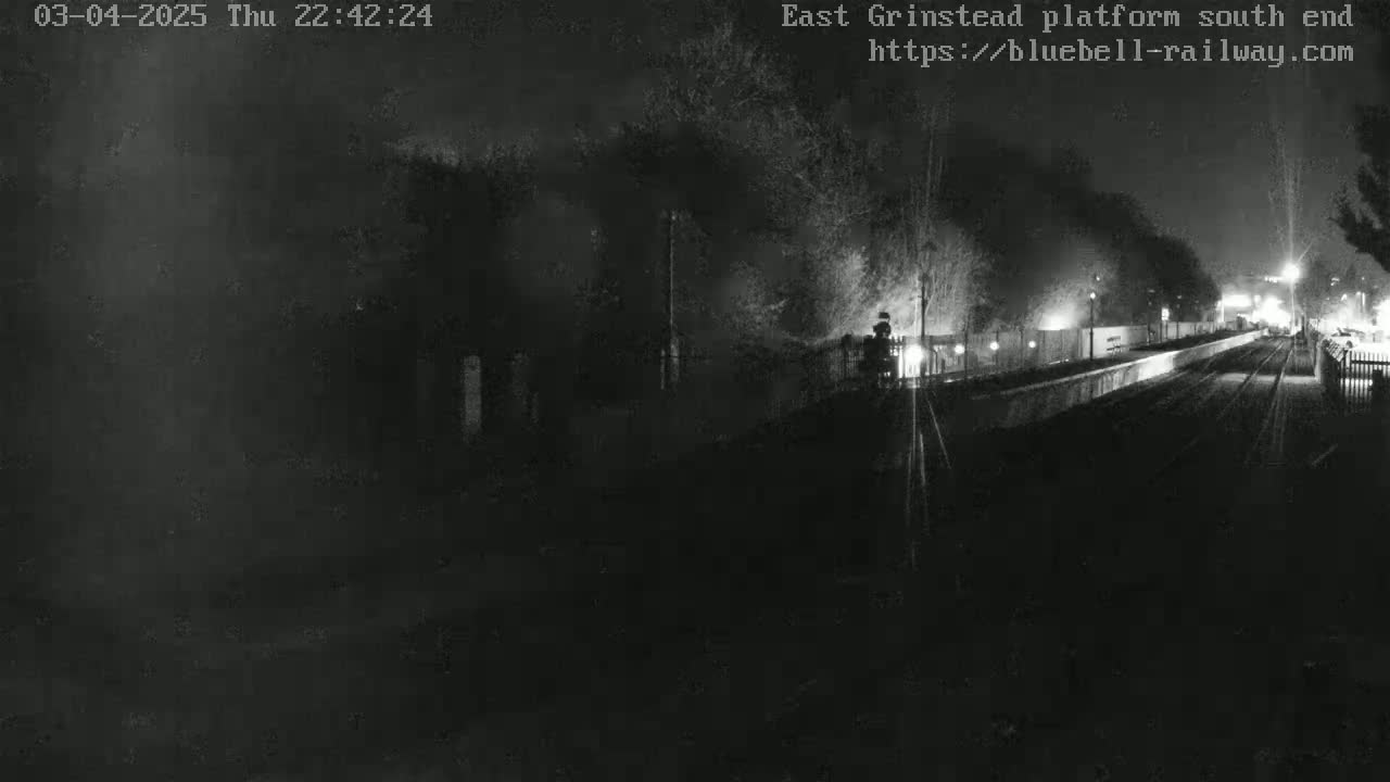 A nighttime, dimly lit view of a train platform and tracks.