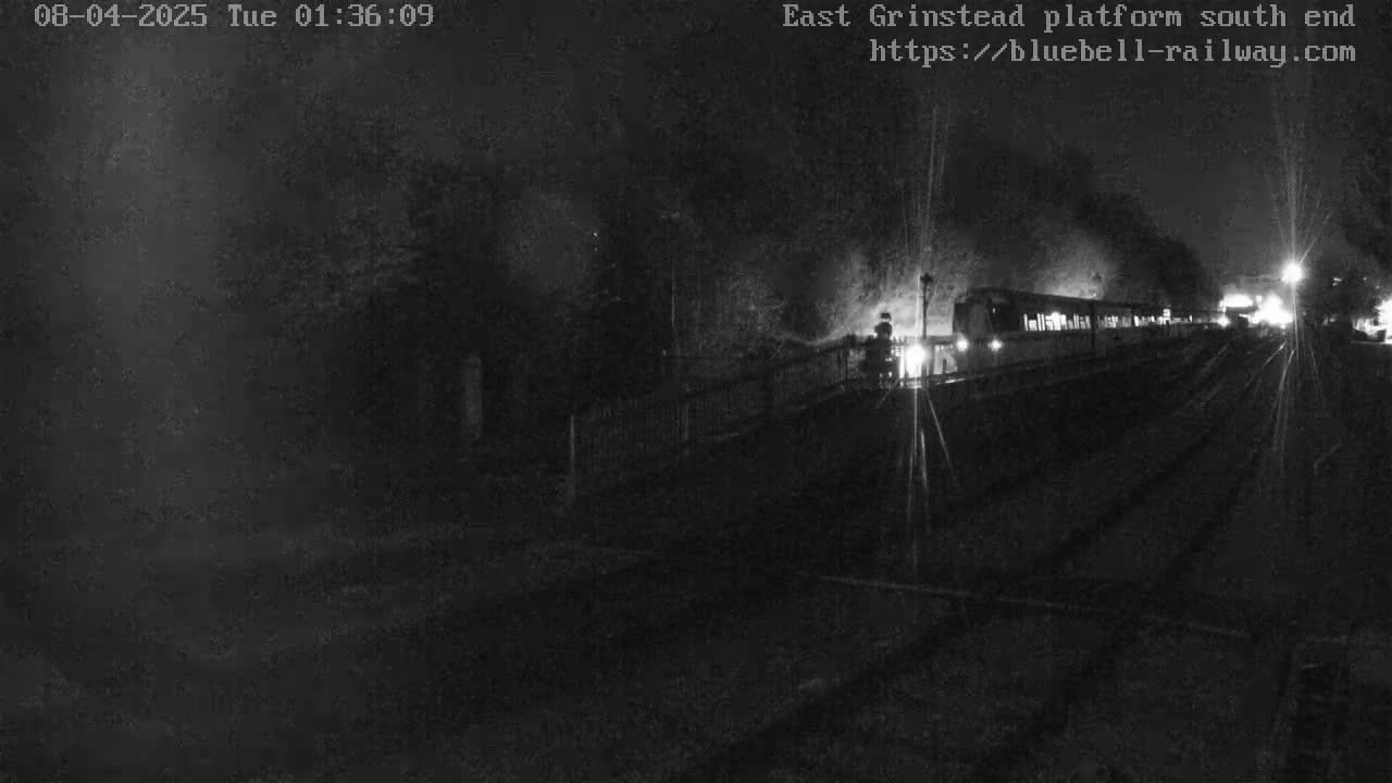 A nighttime, low-light image shows a train departing a station.