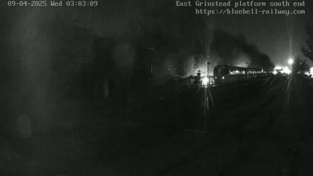 A dimly lit train departs from a platform at night.