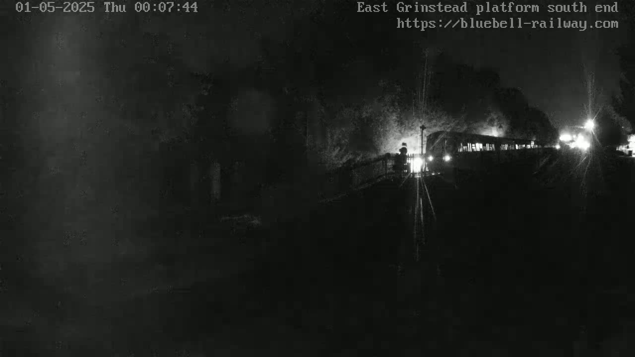 A dimly lit train is visible at night, partially obscured by darkness.