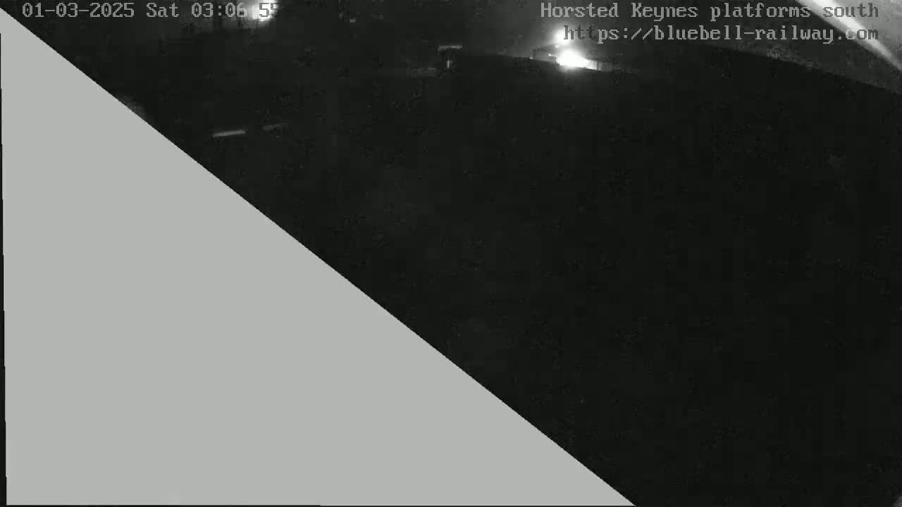 A nighttime, low-light view of a dark area, possibly a train platform, with a gray triangle obscuring a portion of the image.
