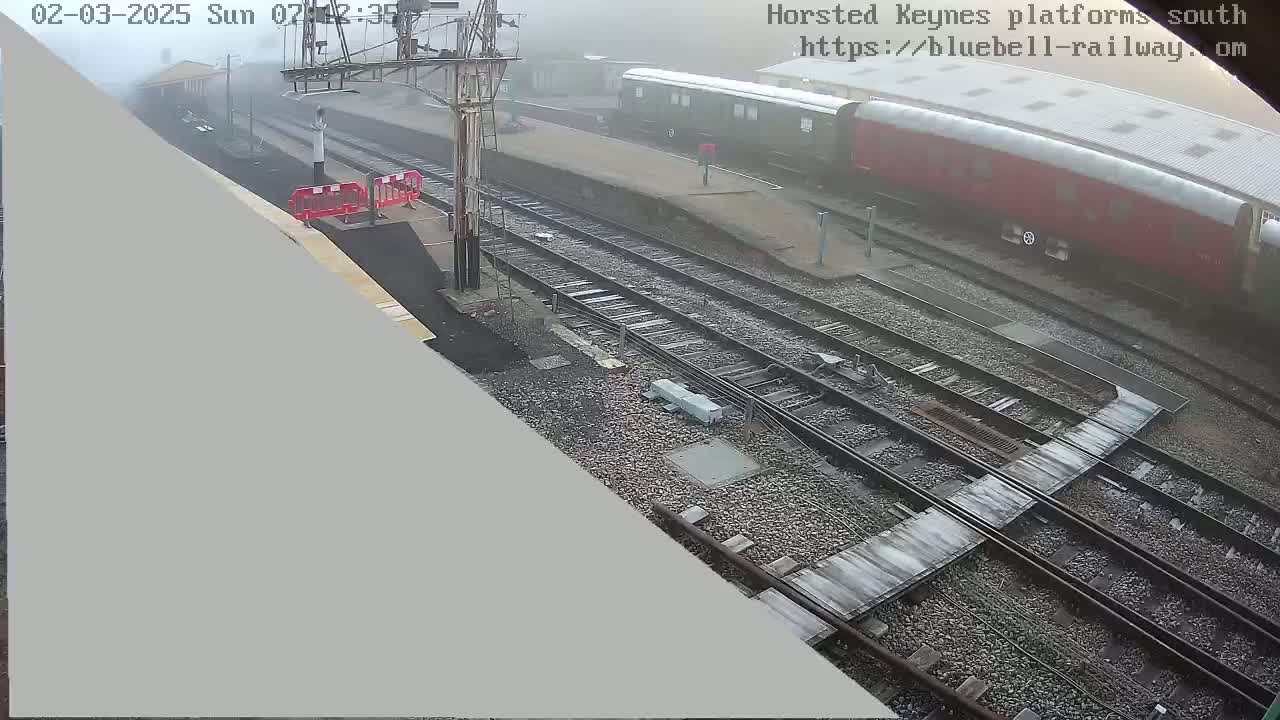 A foggy view of a train station with several railway tracks and a parked train.