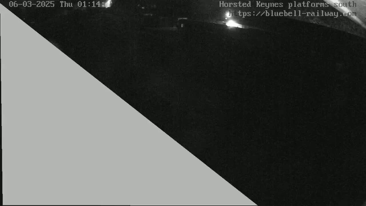 A nighttime, low-light image shows a dark area, possibly a train platform, bisected diagonally by a lighter gray area.
