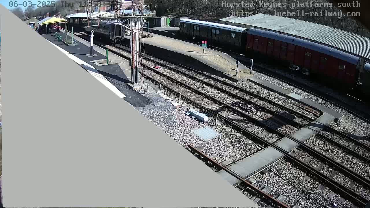 A high-angle, sunny view of a railway station with multiple train cars and tracks.