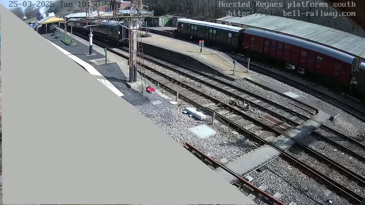 A high-angle view of a railway station on a sunny day, showing several railway cars and train tracks.