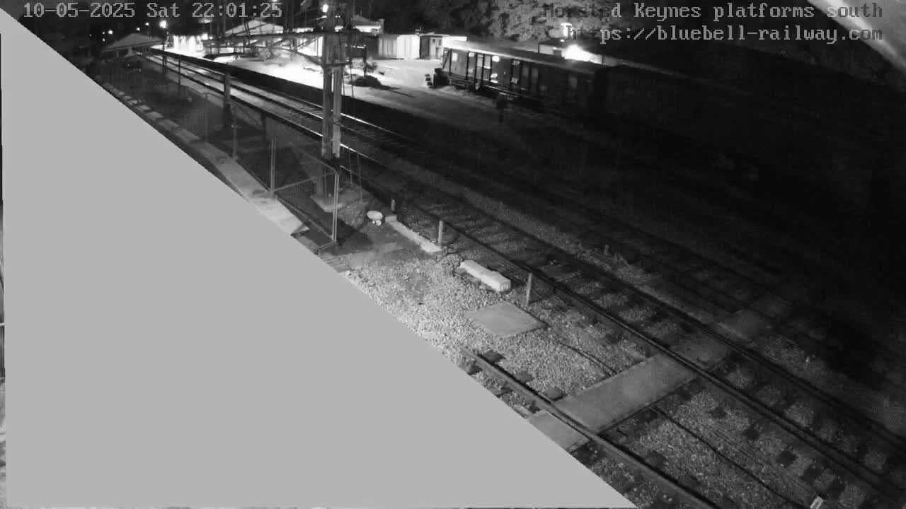 A nighttime view of train tracks and a railway car parked at a station.