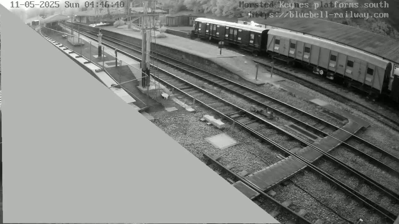 A black and white, high-angle view shows a train at a railway station platform.