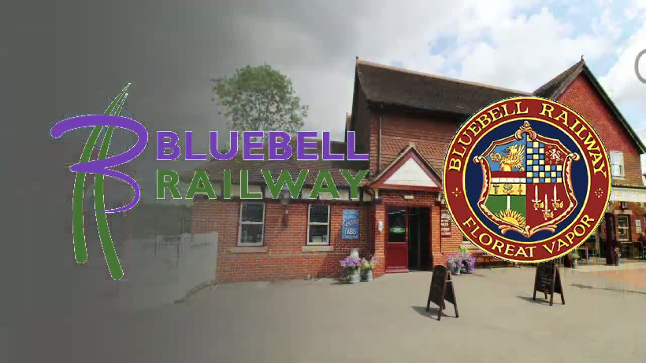 A brick building with a red door, under a partly cloudy sky, is situated next to a large circular emblem.