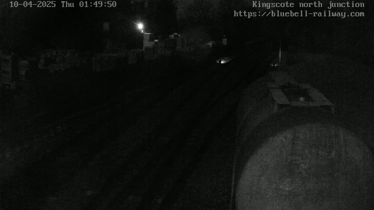 A nighttime, low-light view of a train on tracks at a railway junction.
