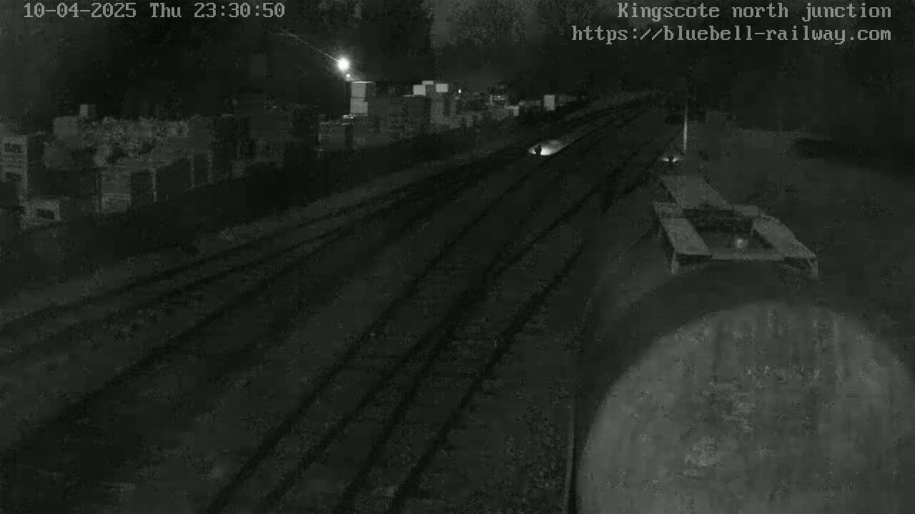 A nighttime, low-light view of a train yard with multiple sets of train tracks extending into the distance.