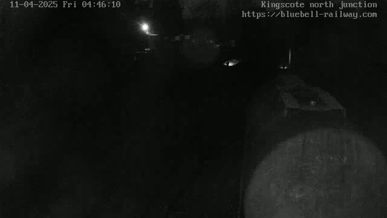 A nighttime, low-light view shows a dark, possibly industrial, area with faint illumination in the distance.