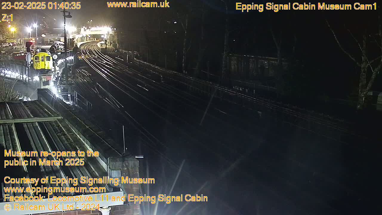 A nighttime view of a train yard with a single train car visible, illuminated by artificial lights.