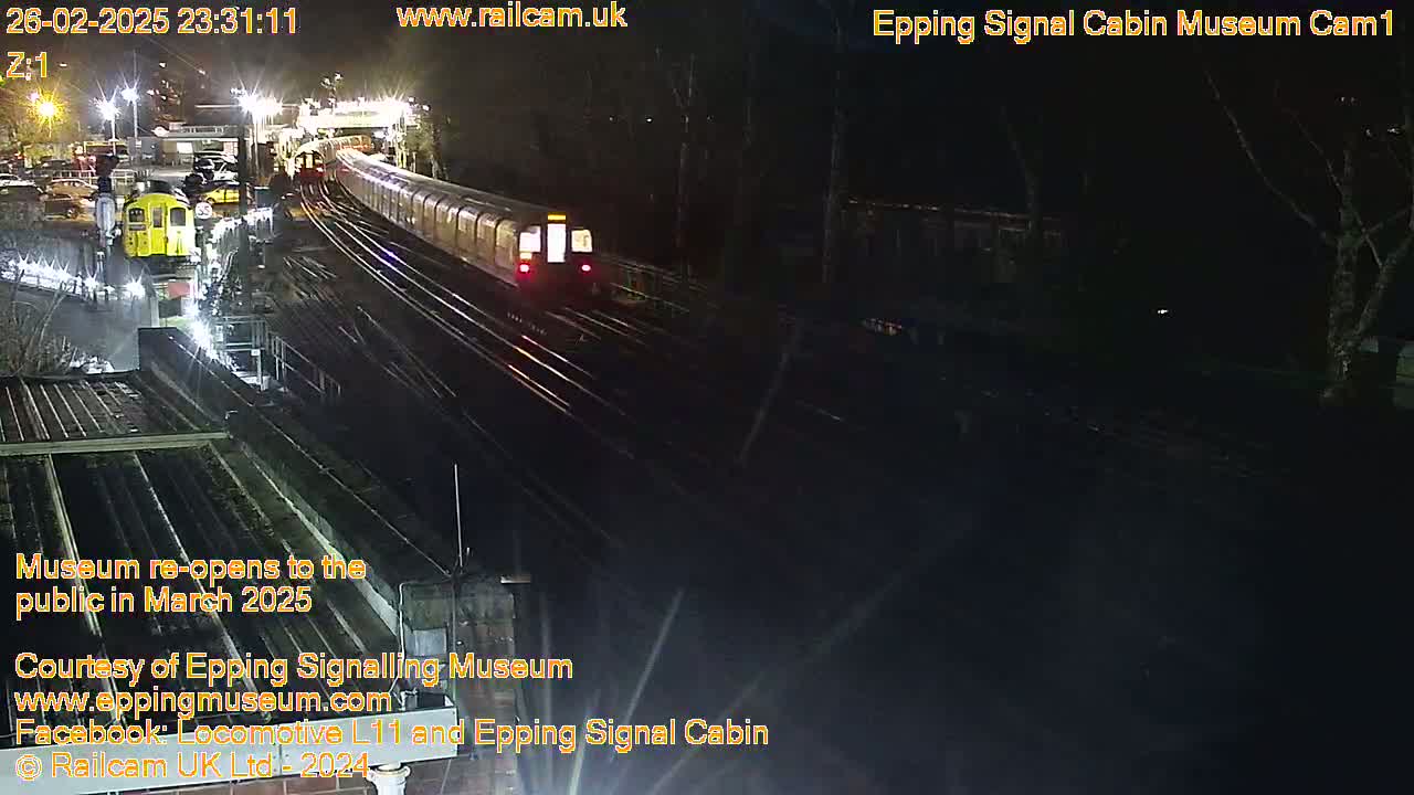 A nighttime view of a train station with a subway train passing by on the tracks.