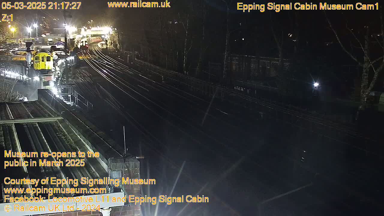 A nighttime view of a train station with multiple train tracks and a single train visible under artificial light.