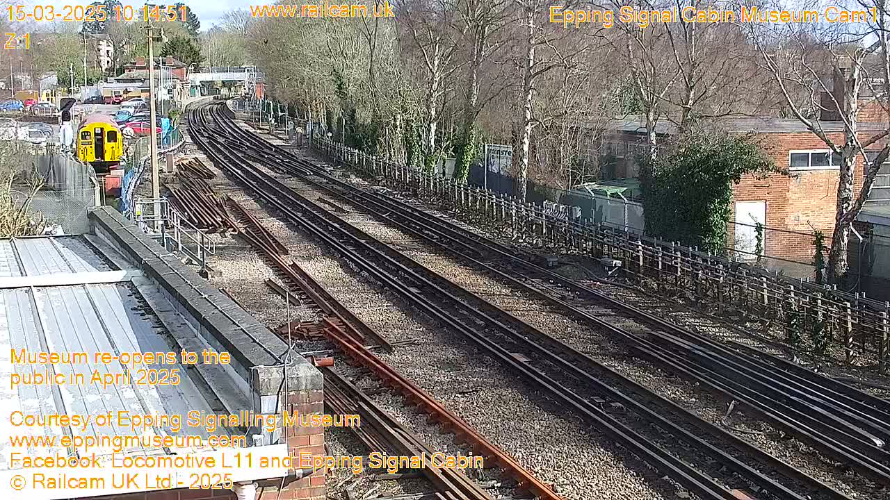 A sunny day reveals multiple train tracks curving through a railway yard, with a train visible in the distance.