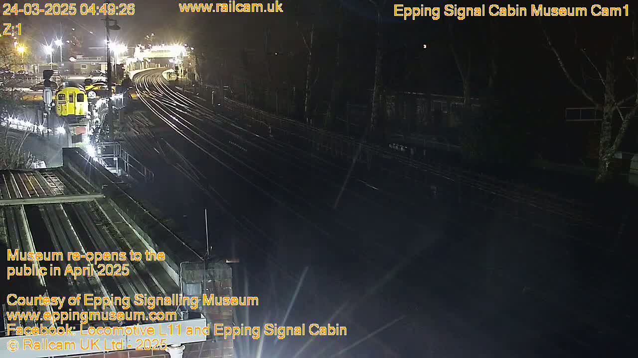 A nighttime view of a train yard with a single train visible, illuminated by artificial lights.