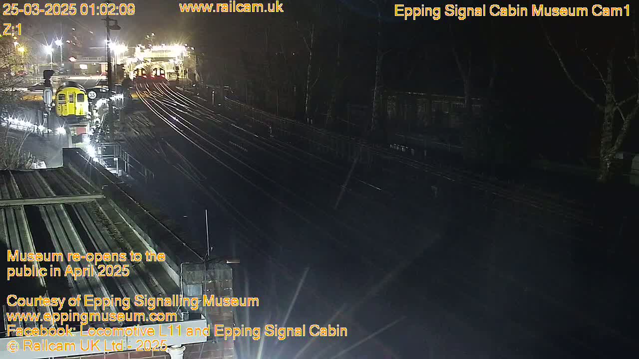 A nighttime view of a train station with multiple train tracks and a partially visible train.