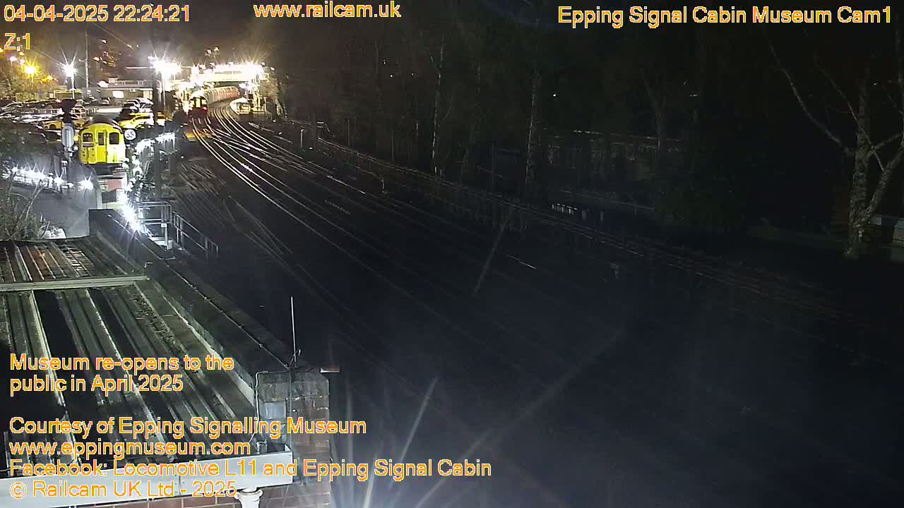 A nighttime view of a train station with several train cars visible and train tracks extending into the darkness.
