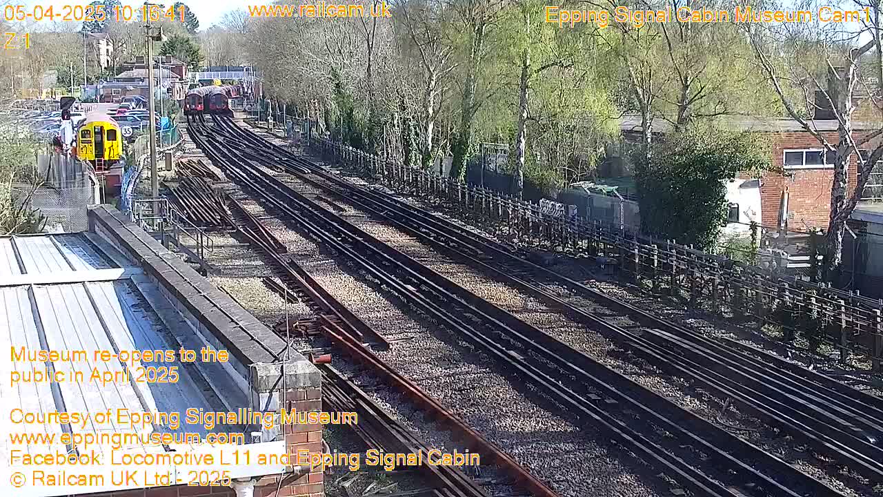 Multiple train tracks with a train and other rail cars visible on a sunny day.