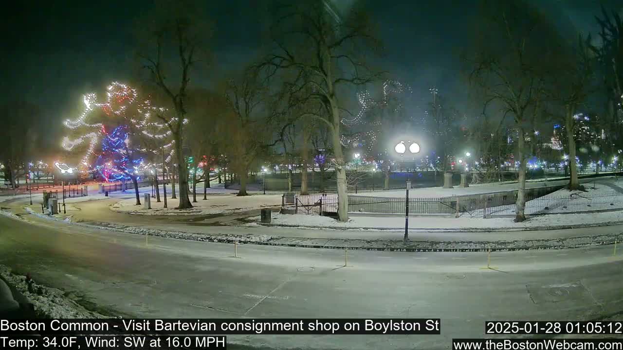 A snow-covered park at night with Christmas lights illuminating trees and pathways, under a dark sky with a southwest wind.