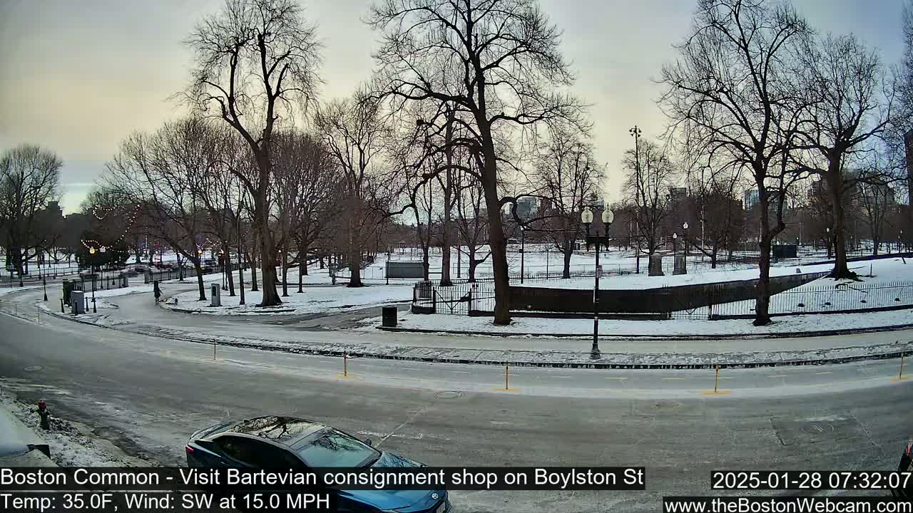 A snow-covered park with bare trees is visible from a street, where a car is parked, under a partly cloudy sky with a southwest wind of 15 mph and a temperature of 35 degrees Fahrenheit.