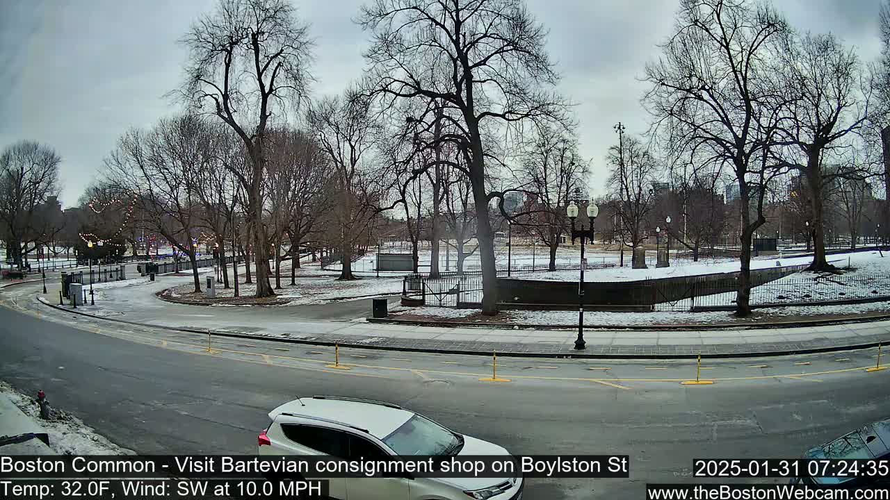 A mostly clear, cold day in a park with bare trees and some snow on the ground, viewed from a street with a car parked nearby.