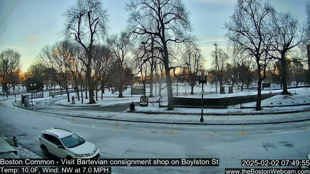A snow-covered park with bare trees and a white SUV is visible on a partly sunny, cold morning with a northwest wind.