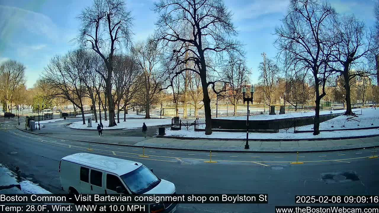 A partly sunny winter day shows a snow-dusted park with bare trees and a street with a white van.