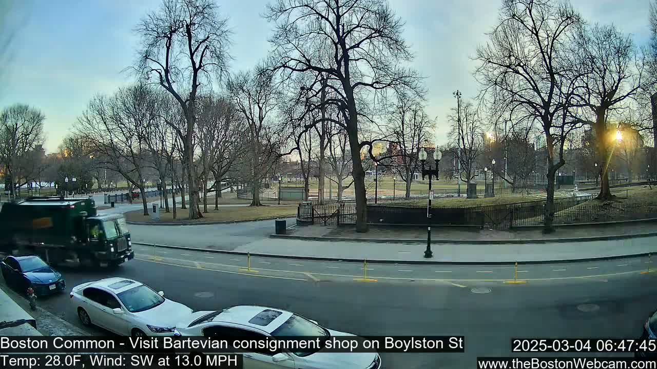 A partly sunny, cool day with a southwest wind shows a street scene near a park with bare trees and several cars.