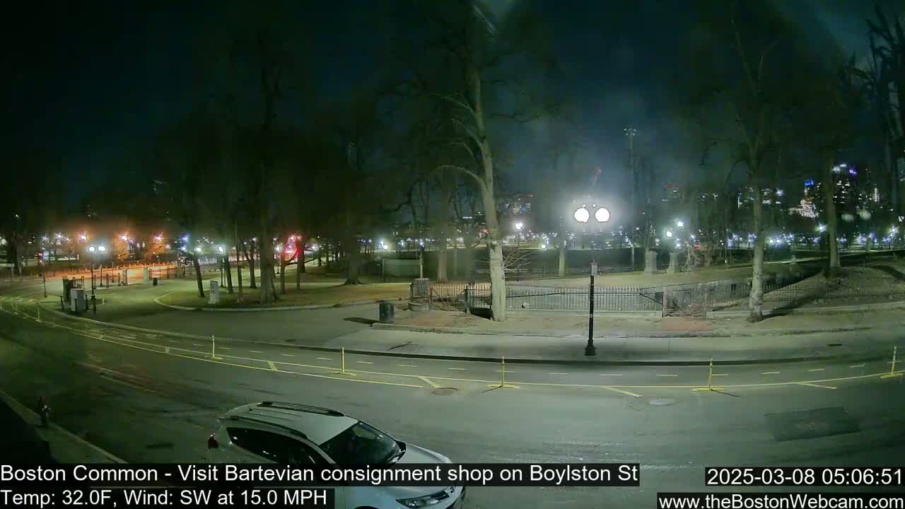 A nighttime view of a park with a road curving through it, illuminated by streetlights, under a partly cloudy sky with a 15 mph southwest wind and a temperature of 32 degrees Fahrenheit.