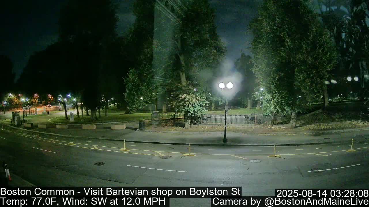 A nighttime view of a park and roadway, with a southwest wind at 12 mph and a temperature of 77 degrees Fahrenheit.