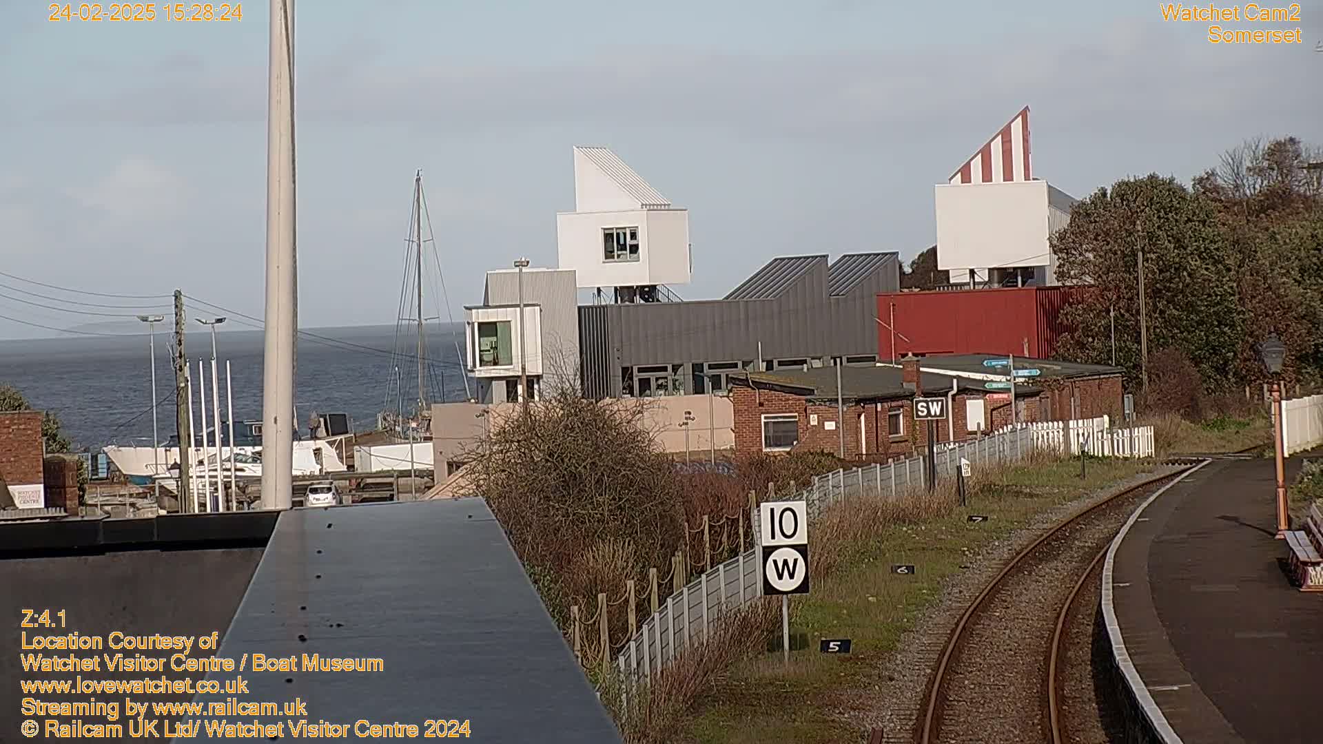 A view of a harbor with modern buildings and a train track, under a clear, sunny sky.