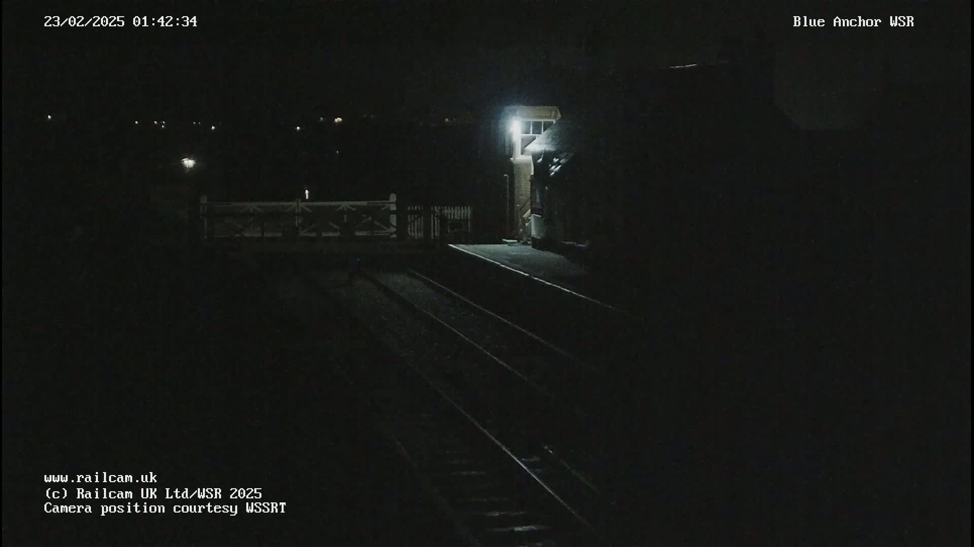 A dimly lit nighttime view of a train platform and tracks.
