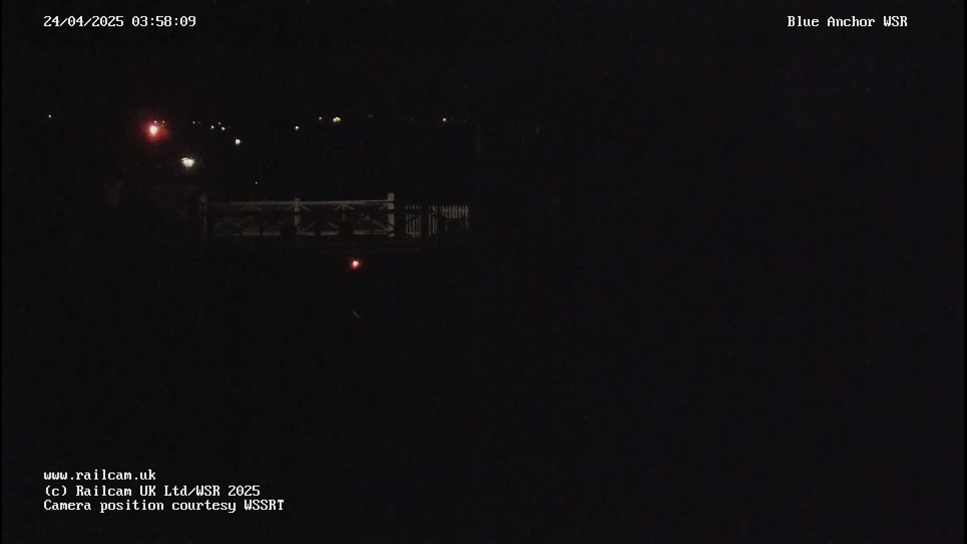 A nighttime, dark view of a bridge with a few distant lights visible.