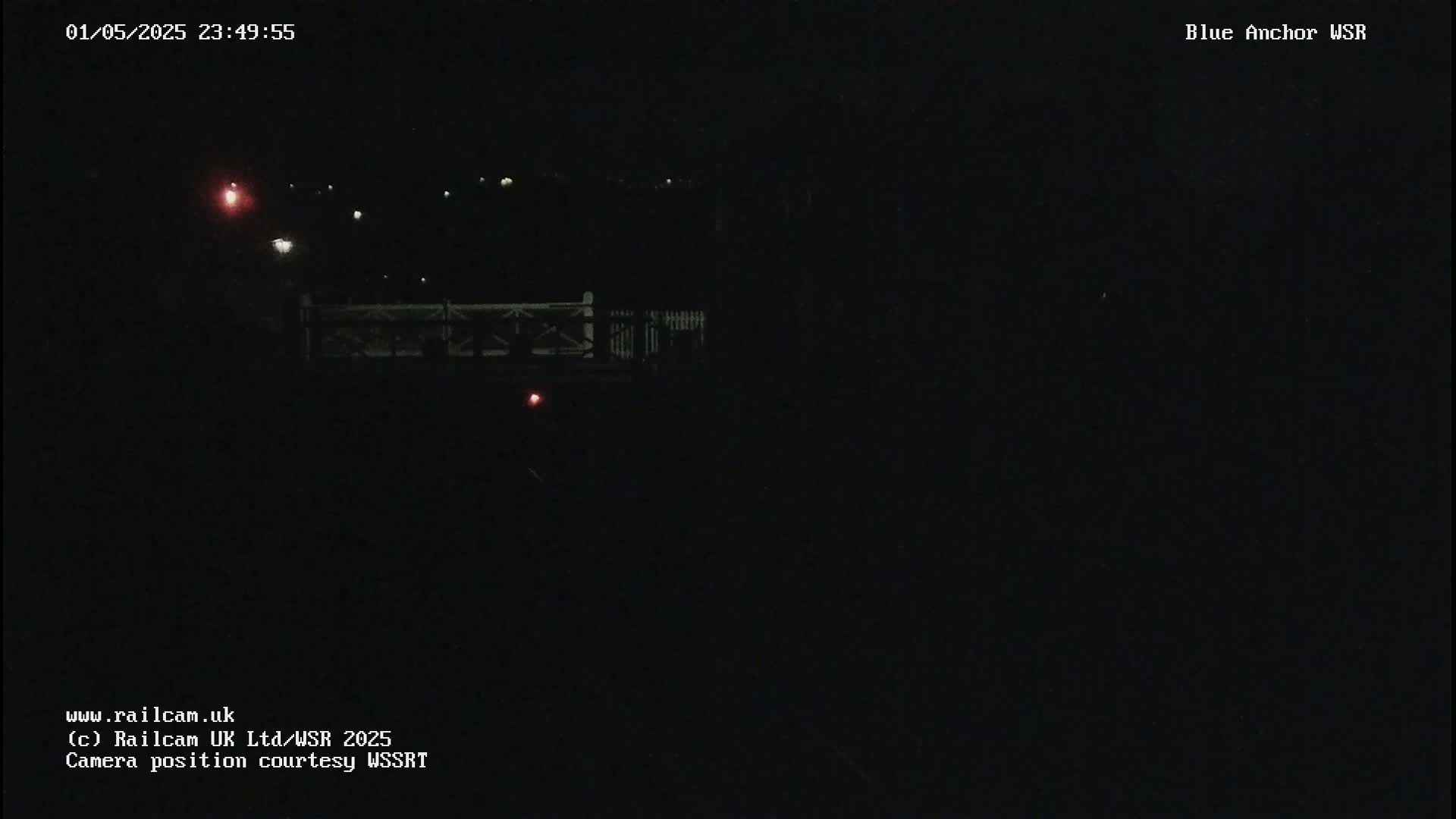 A nighttime, low-light view of a bridge with a few distant lights visible.