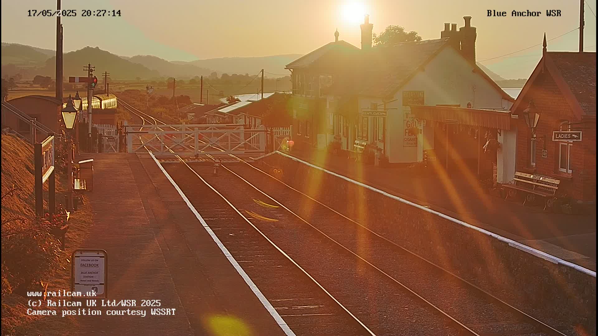 A train sits at a rural train station at sunset, bathed in golden light.