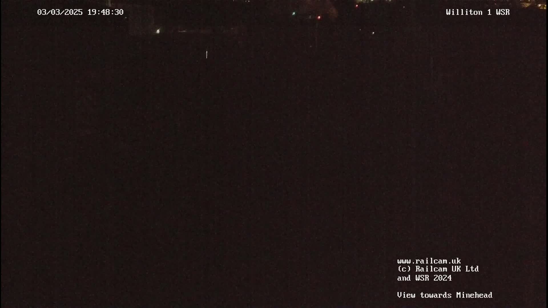 A dark, nighttime view of a mostly black landscape with a few distant lights.